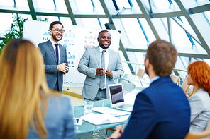 Multi-ethnic professionals presenting financial data to co-workers