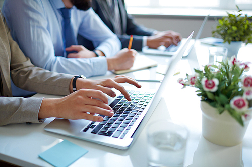 Hands of businesswoman typing on laptop at workplace