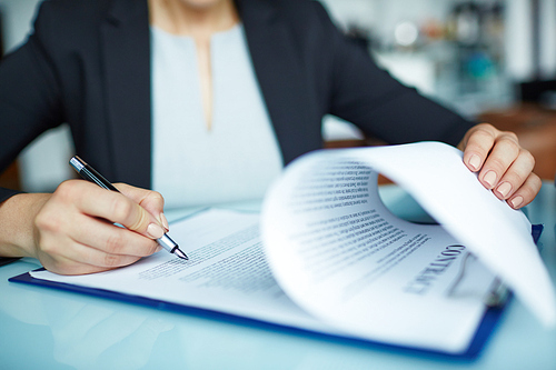 Human hand with pen over business contract