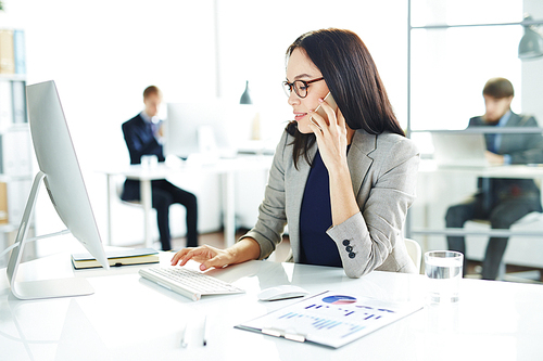 Businesswoman speaking on the phone and browsing online