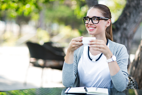 Pretty businesswoman with cup of coffee sitting in cafe