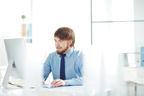 Contemporary businessman looking at monitor in office