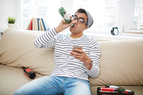 Guy with bottle drinking beer and reading sms