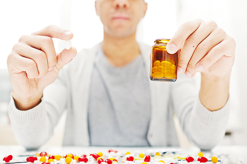 Young man holding medical bottle with pills
