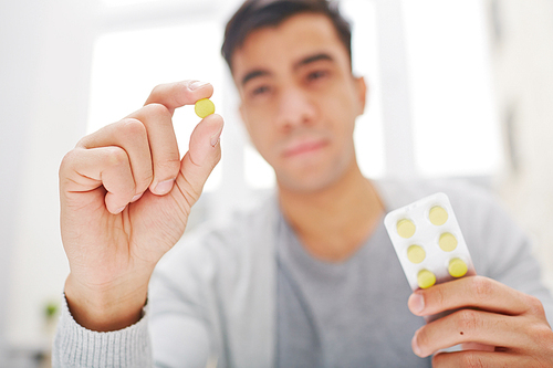 Young man holding round yellow pill