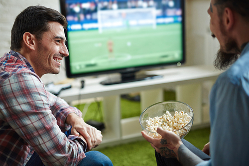 Modern men talking while watching football broadcast