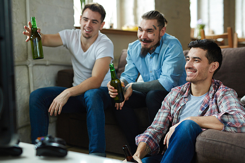 Group of guys with beer sitting in front of tv set and watching football match