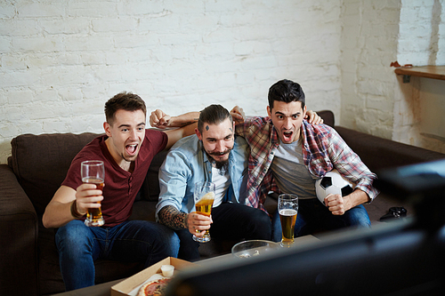 Company of guys with beer expressing excitement by goal of their favorite football team