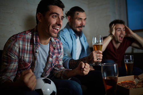 Excited guy and his friends spending time in pub and watching football match