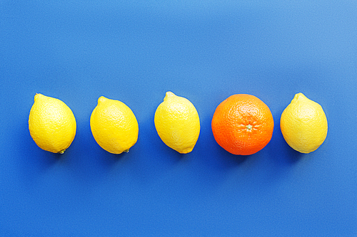 Row of lemons with one orange