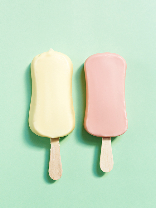 Pink and yellow ice-creams on light green background