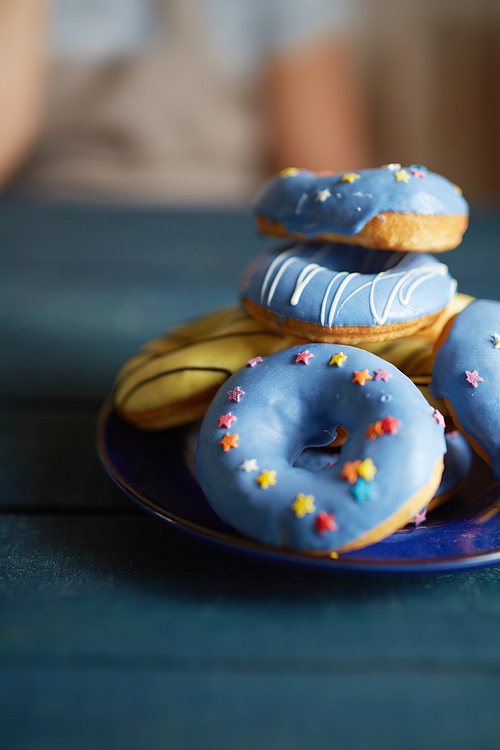 Heap of doughnuts with blue icing and decorative stars on plate