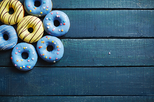 Blue wooden boards with group of tasty donuts on top