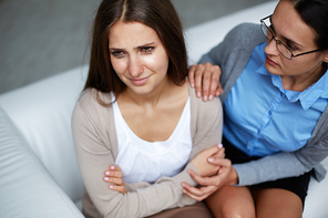 Hopeless girl weeping with psychologist reassuring her