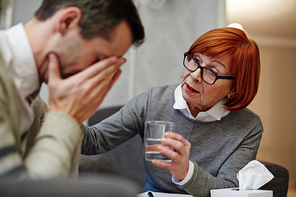 Psychologist offering glass of water to her crying patient