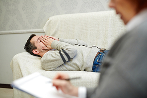 Frustrated man lying on couch while visiting counselor