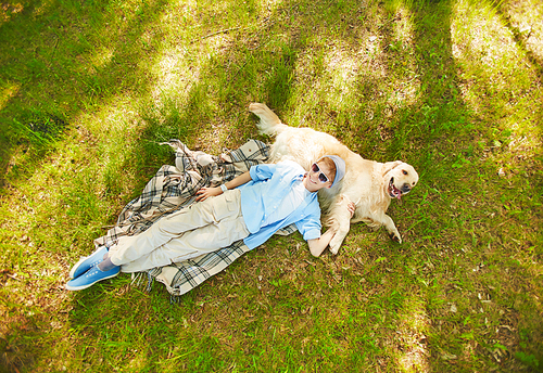 Teenage boy lying on blanket with his dog