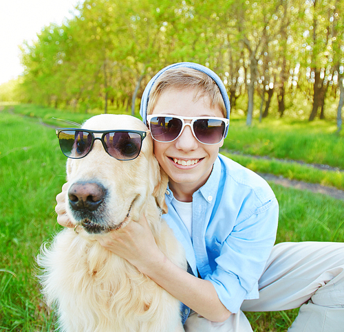 Portrait of happy teenage boy and his dog in sunglasses
