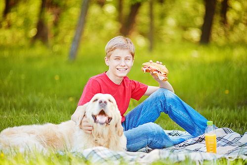 Teenage boy resting with his dog and having a bite