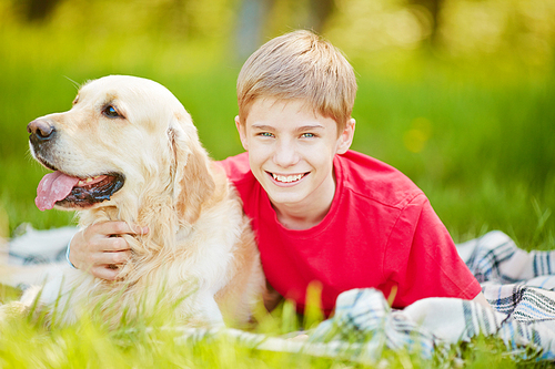 Portrait of a happy teenage boy embracing his dog