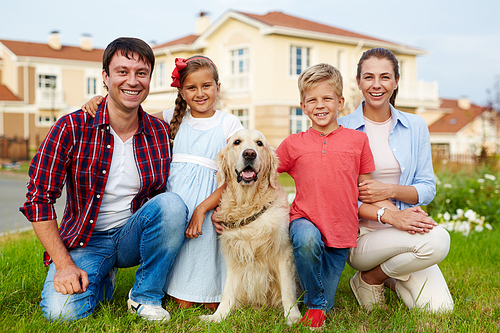 Family members and their dog sitting on grass by new house