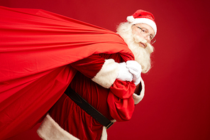 Santa carrying big red sack with xmas presents