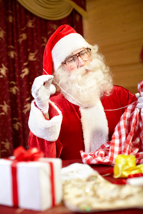 Santa Claus sitting at the table and preparing gifts for Christmas