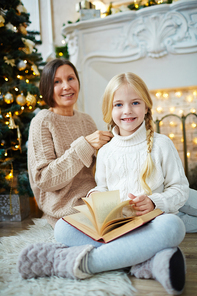 Cute girl with open book  with grandmother on background