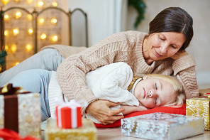 Grandmother lying by her sleeping granddaughter on the floor