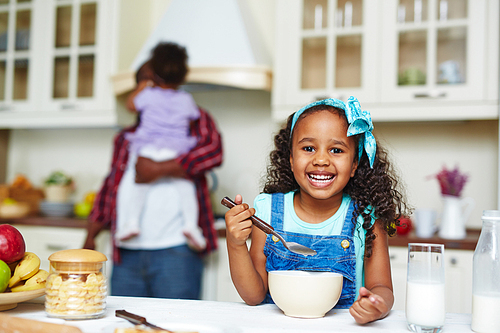 Happy African-American girl eating morning cornflakes