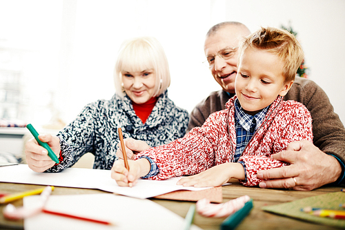 Cute child and his grandparents drawing with highlighters