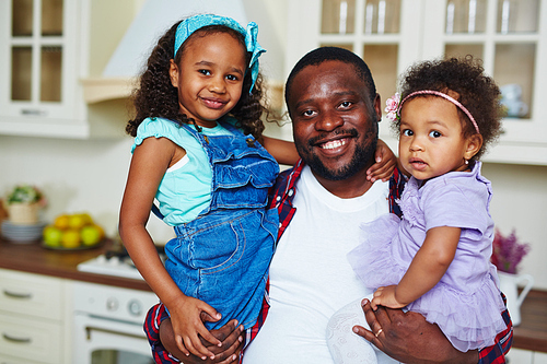 Young man holding his cute daughters in arms