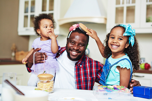 Happy little girl playing with her father at home