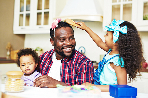 Youthful girl playing hairdresser with her father