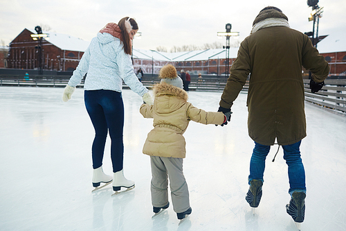 Rear view of mother, father and daughter skating at leisure