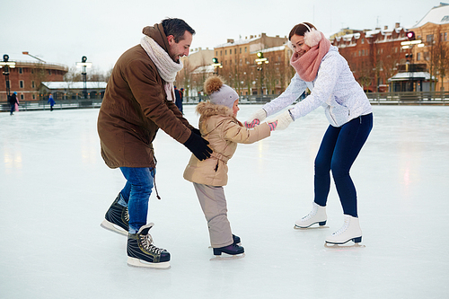 Young parents teaching their daughter to skate