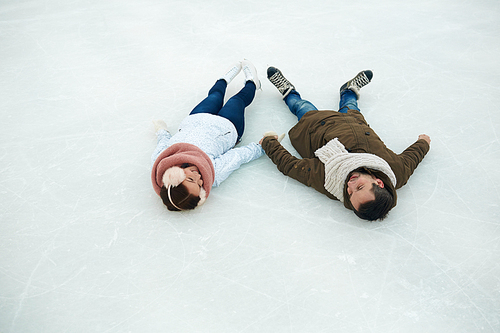 Young couple of skaters lying on ice