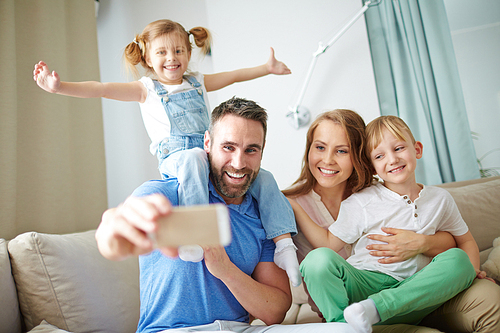 Happy family of four making selfie at home