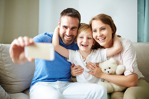 Affectionate family making selfie on cellphone