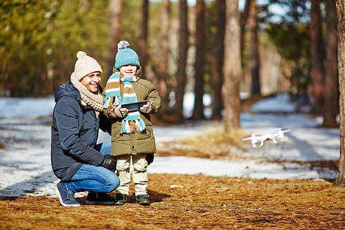 Man and his son driving drone from touchpad outdoors