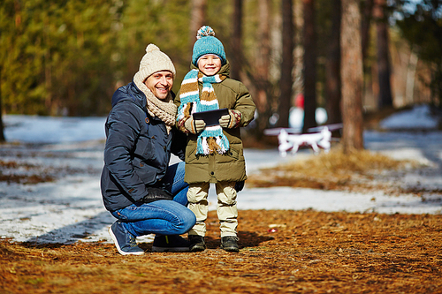 Kid and parent looking after flying drone in park