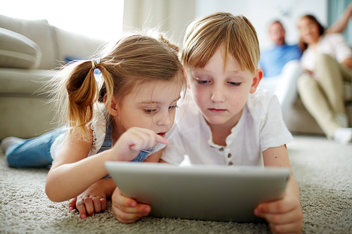 Modern kids with touchpad networking with parents on background