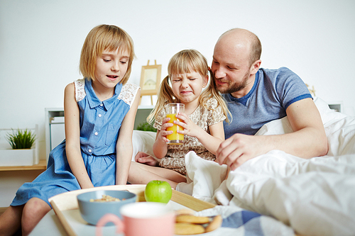 Father and his daughters having breakfast in bed