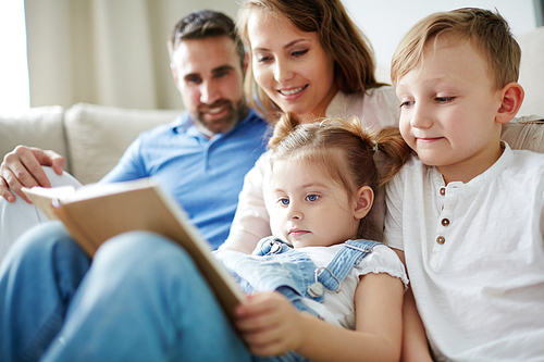 Family of four reading book at leisure