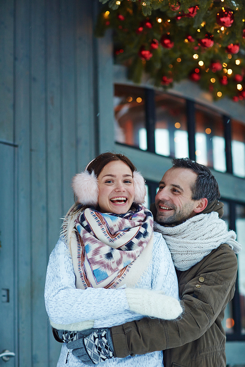 Happy man embracing his laughing wife on xmas eve outdoors