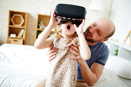 Father looking at his amazed daughter with vr headset