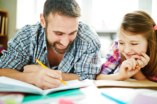 Happy man drawing in copy-book with his daughter near by