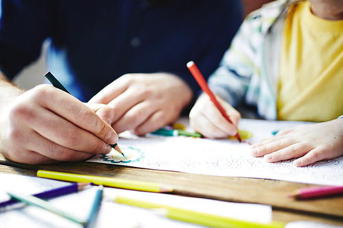 Parent and kid coloring pictures with pencils