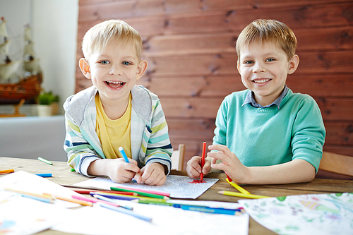 Two happy boys drawing with highlighters