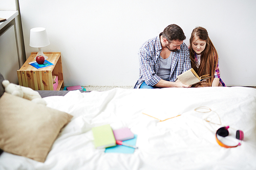 Teenage girl and her father reading at home